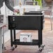 A man using a Choice black beverage cooler cart to chill bottles of beer outdoors.