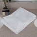 An Oxford Regale white bath towel on a white counter top.