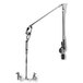 A T&S wall-mounted pre-rinse faucet with a long silver metal pipe and a metal arm with a long handle and a hook.