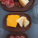 An American Metalcraft rimmed ash wood serving board with cheese and meat on a table.