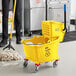 A man using a yellow Lavex mop to clean a floor with a yellow Lavex mop bucket.