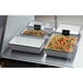 A white rectangular American Metalcraft container with black rim filled with food on a buffet.