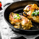 Two chicken breasts cooking in a Lodge cast iron skillet with parsley on top.