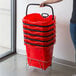 A woman holding a stack of red Regency shopping baskets.