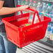 A person holding a red Regency shopping basket.