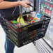 A person holding a Regency shopping basket full of groceries including fruit and vegetables.