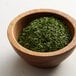 A bowl of Regal parsley flakes on a white surface.