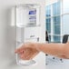 A hand using a Purell hand sanitizer dispenser.