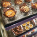 An Alto-Shaam heated display case filled with muffins and pastries on a bakery counter.