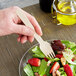 A person holding an Eco-gecko wooden fork over a salad.