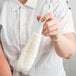 A person using a Franmara glassware washing brush with a white foamy loop to clean a glass.