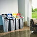 A row of Rubbermaid Slim Jim yellow recycling bins in a corporate office cafeteria.