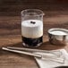 A silver bowl with white liquid in it next to a bowl of whipped cream and a stainless steel mini bar whisk.