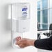 A person using a white Purell hand sanitizer dispenser.