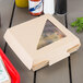 A Bagcraft corrugated take-out box with a pizza slice inside and a plastic window.