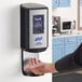 A person using a Purell automatic hand sanitizer dispenser.