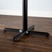 A Lancaster Table & Seating black metal bar height table base on a wood floor.