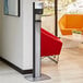 A Purell black automatic hand sanitizer dispenser on a graphite floor stand in a corporate office cafeteria.