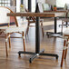 A Lancaster Table & Seating black cast iron table base with a black column on a table in a restaurant.