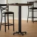 A black Lancaster Table & Seating bar height table base with FLAT Tech levelers.