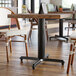 A Lancaster Table & Seating black cast iron table base with FLAT Tech levelers under a restaurant table.