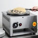 A person using a Carnival King hot plate to cook a pancake.