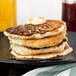 A stack of Krusteaz buttermilk pancakes with syrup and butter on top.