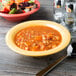 A bowl of soup next to a bowl of salad on a table.