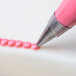 A close-up of a pink liquid being piped with an Ateco oval tip.