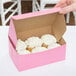 A pink bakery box with cupcakes inside.