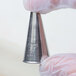 A person holding a metal Ateco oval piping tip in their hand.