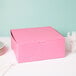 A pink bakery box with a lid on it.