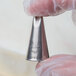 A person holding a metal Ateco 2-hole piping tip.