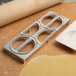 A metal Fox Run dumpling maker and rolling pin on a table.