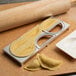 A Fox Run metal dumpling maker with a piece of dough and a rolling pin.