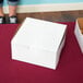 A white pie / bakery box on a red table.