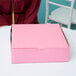 A woman sitting at a table with a pink pie box.