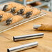 A close up of a Fox Run cannoli mold on a table with pastries.