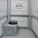 A light grey PolyJohn wheelchair accessible portable restroom with a black seat.