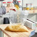 A person pouring food into a plastic bag on a counter.