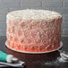 A frosted cake on a 16" white corrugated cake circle on a table.