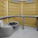 A tan PolyJohn wheelchair accessible portable restroom with a toilet and sink.