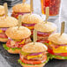 A tray of mini burgers with Royal Paper Eco-Friendly Bamboo Paddle Picks on a table.