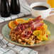 A plate of food with Kunzler bacon, eggs, and coffee on it.