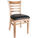 A Lancaster Table & Seating wooden restaurant chair with a black vinyl seat.