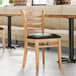 A Lancaster Table & Seating wood restaurant chair with black vinyl seat detached.