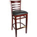 A Lancaster Table & Seating mahogany wood bar stool with a black vinyl seat.