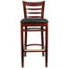 A Lancaster Table & Seating mahogany wood bar stool with a black vinyl seat.