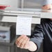 A person holding a paper with writing on it in a restaurant.