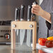 A woman holding a Mercer Culinary Genesis knife with a wood and glass handle.